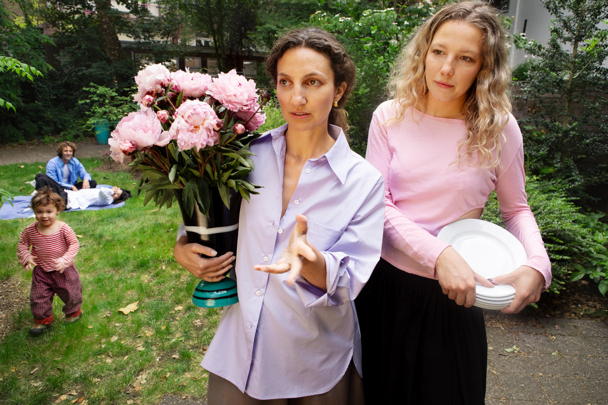 The CARMEN House Shirt in lilac, worn in the garden with a vase of pink peonies